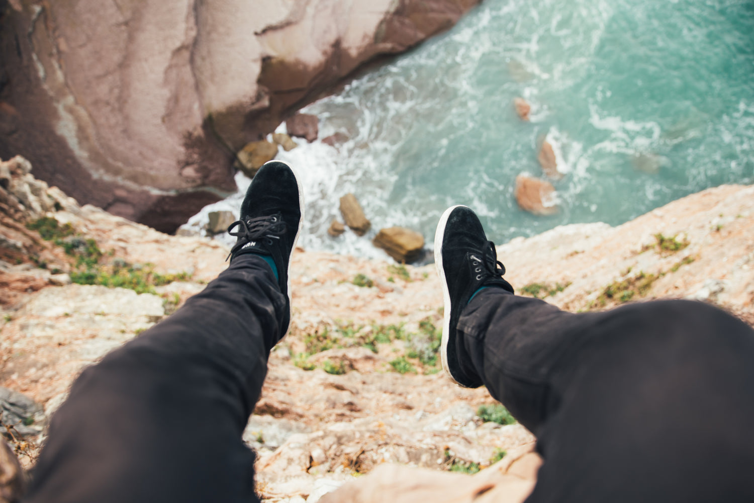 feet with shoes hanging over a cliff